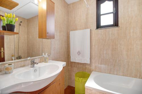 a bathroom with a white sink and a mirror at Apartamento Cali com Piscina in Apúlia