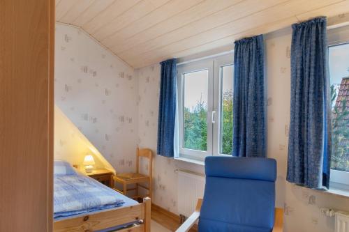 a bedroom with a blue chair and a window at Ferienhaus Poth in Wangerland