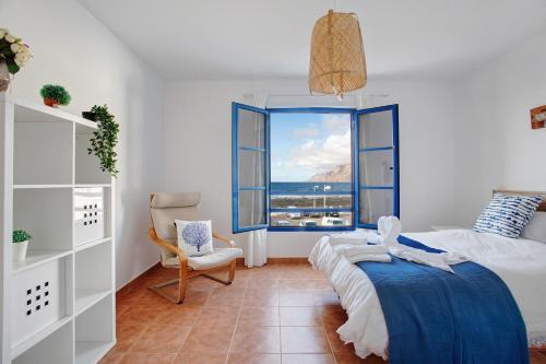 a bedroom with a bed and a chair and a window at Casa Vivo in Famara