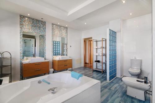 a bathroom with a tub and a toilet and a sink at Villa Rosana in Albufeira