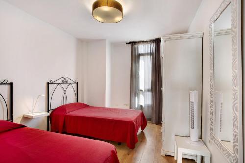 a red bedroom with two beds and a window at Apartamento Playa Morro Jable 1a in Morro del Jable