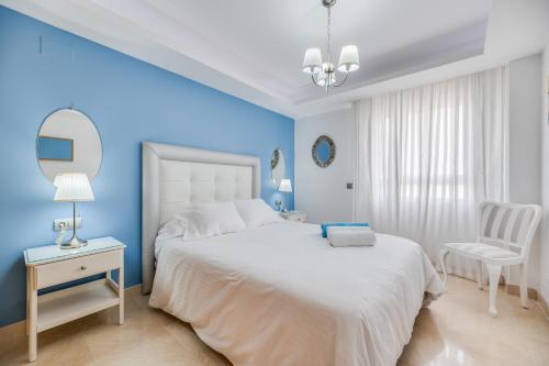 a blue bedroom with a white bed and a chair at Acogedor apartamento 2 dormitorios in Marbella