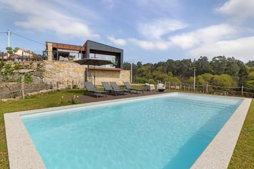 a swimming pool with chairs and a house at Casa Do Mordomo in Arcos de Valdevez