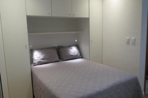 Cama pequeña en habitación pequeña con armarios blancos en Loft Felipe De Oliveira, en Río de Janeiro