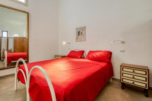 ein rotes Bett in einem Zimmer mit einem Spiegel in der Unterkunft Monolocale Volta in Nardò