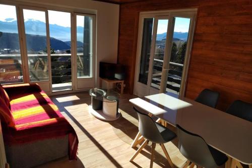 een woonkamer met een tafel, stoelen en ramen bij Foun Vive in Font Romeu Odeillo Via