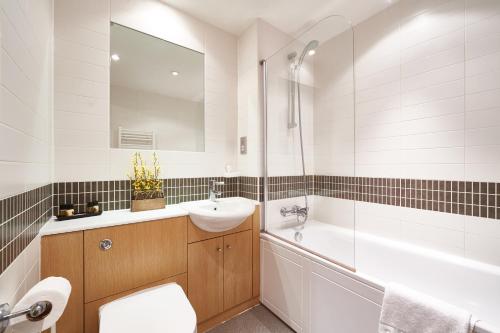 a bathroom with a sink and a toilet and a tub at ShortstayMK Vizion apartments, with free superfast wi-fi, parking, Sky sports and movies in Milton Keynes