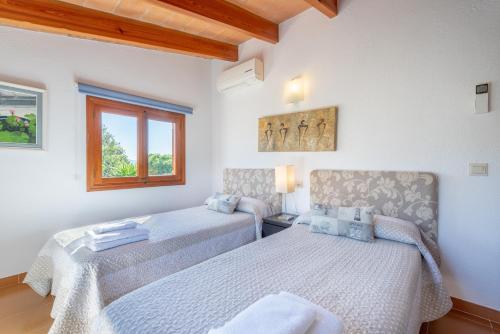 a bedroom with two beds and a window at La Sorteta De Cuxach in Pollença