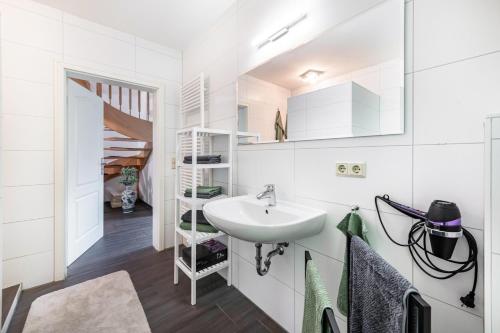 a white bathroom with a sink and a staircase at Großes Ferienhaus Im Grünen - in Dummerstorf