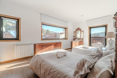 two beds in a bedroom with two windows at Casa Vilarinha Gerês in Bouro