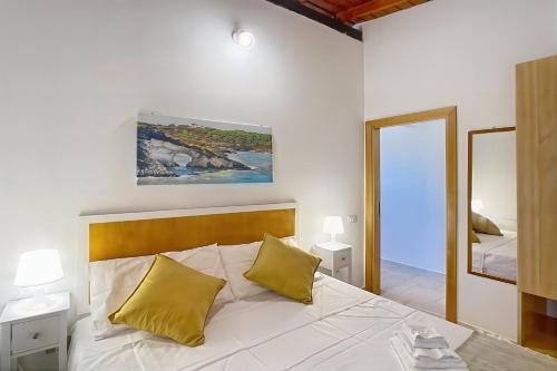 a bedroom with a white bed with two yellow pillows at La Mignola - Casa Vacanze in Vieste