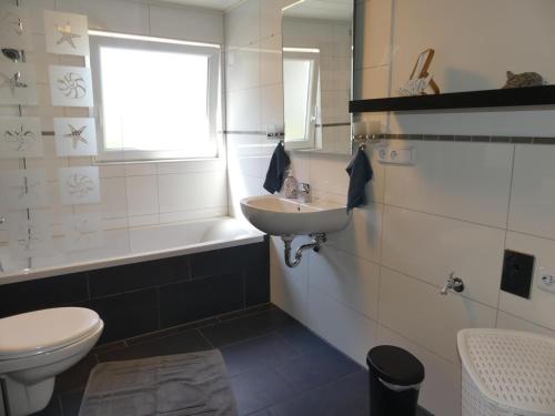 a bathroom with a sink and a toilet and a tub at Ferienhaus Villa Wolffsschlucht in Oberzent