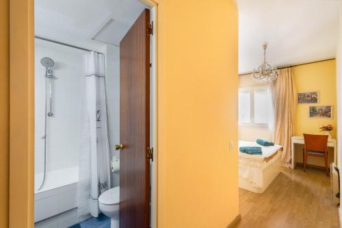 a bathroom with a shower and a toilet and a bedroom at Oasis in Sitges