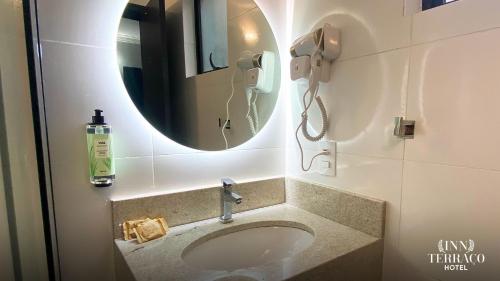 a bathroom with a sink with a mirror and a phone at INN TERRAÇO Hotel in Mirandópolis