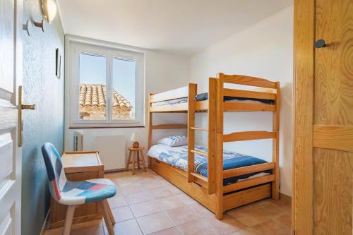 a bedroom with two bunk beds and a chair at L'amourié, Rdc, Gîte 4 Personnes in Sainte-Croix-de-Verdon