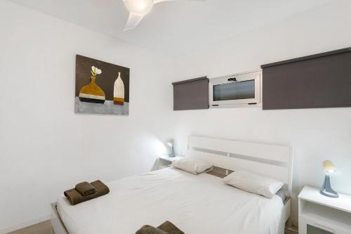 a white bedroom with two beds and a tv at Nice Apartment 1210 In Central Area in San Bartolomé
