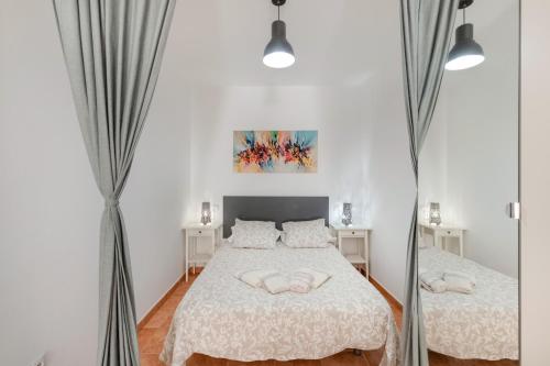 a white bedroom with two beds and a mirror at Vv Estrella in Puerto de Mogán