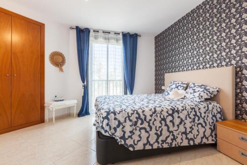 a bedroom with a bed and a window with blue curtains at Cubelles mar in Cubelles