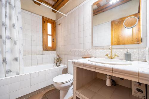 a white bathroom with a toilet and a sink at El Clos 1 in Conesa
