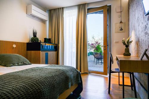 a bedroom with a bed and a desk and a window at Maravida Vacation Rooms in Dobrovo