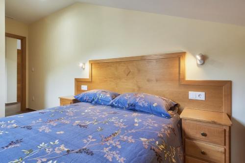 a bedroom with a blue bed with a wooden headboard at Valle del Ibias - Segundo Izquierda in Cecos