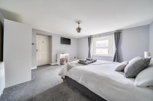 a white bedroom with a large bed and a window at Cosy Apartment above Village Pub in Buxton