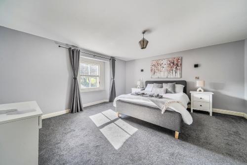 a white bedroom with a bed and a window at Cosy Apartment above Village Pub in Buxton