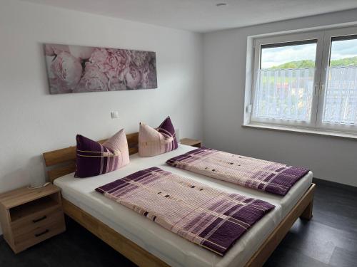 a bedroom with a bed with purple pillows and a window at Ferienwohnung S Keller in Plankenfels