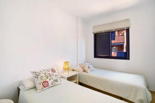 two beds in a white room with a window at Meloneras 1 in Maspalomas