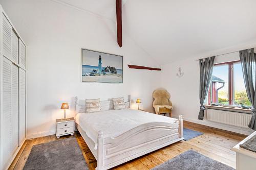 a white bedroom with a white bed and windows at Wat'n Utkiek in Rodenäs