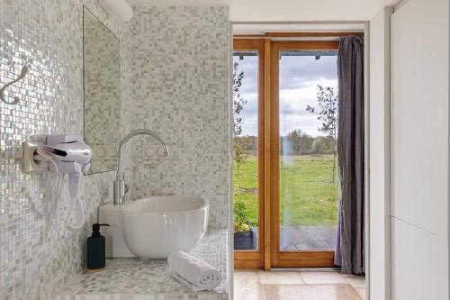 a bathroom with a tub and a sink and a window at Petit Prépinson - La Trigalière in Ambillou