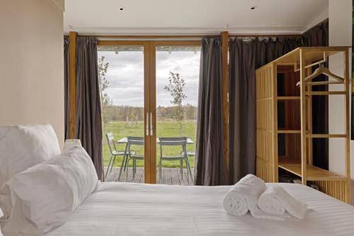 a bedroom with a bed and a balcony with a table at Petit Prépinson - La Trigalière in Ambillou