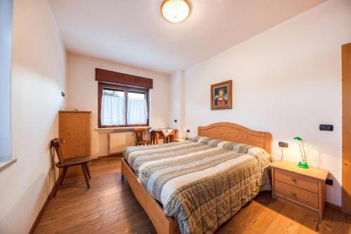 a bedroom with a bed and a table and a window at La pratolina piano terra in Castello di Fiemme