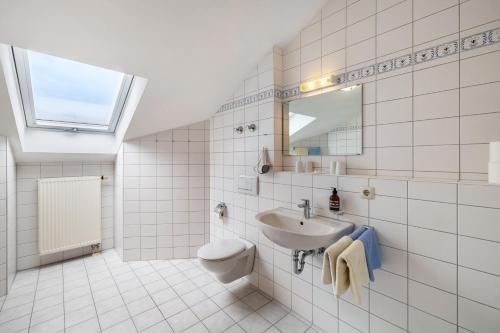 a white tiled bathroom with a sink and a toilet at Fewo Brünnstein - Zimmer 65 in Oberaudorf