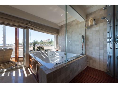 a large bathroom with a tub and a large window at Chalet en la playa San Agustin in Maspalomas