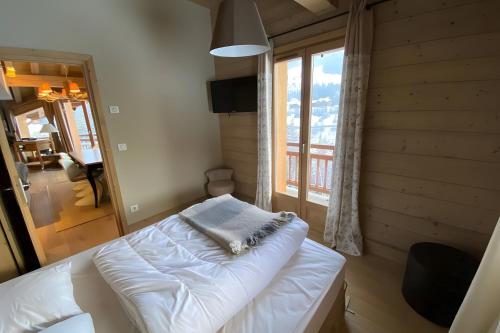 a bedroom with a bed and a large window at Les Craterelles 3 - 1650 in Courchevel