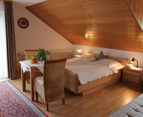 a bedroom with a large bed and a table with a table at Gästehaus Heimenberg in Bad Rippoldsau-Schapbach