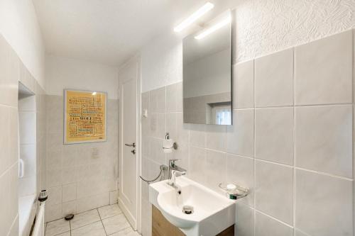 a white bathroom with a sink and a mirror at Ferienwohnung Holterhoff in Olpe