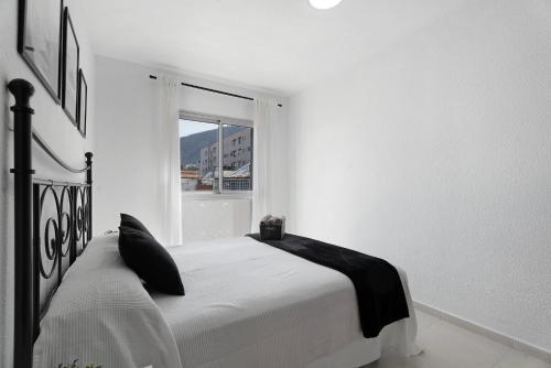 a white bedroom with a bed and a window at Apartamento Opuntia in La Orotava