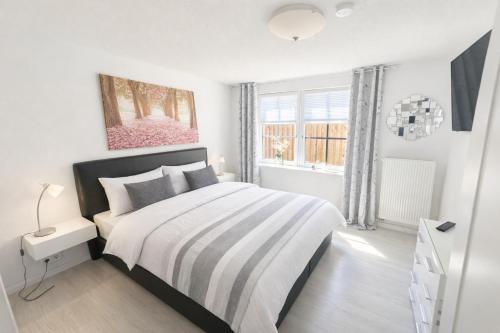 a white bedroom with a bed and a window at Huus ant Kornfeld Erdgeschoss in Osteel