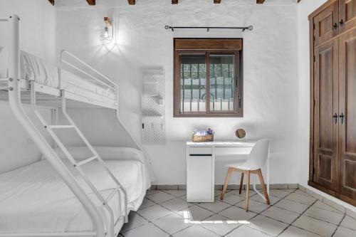 a white bedroom with a bunk bed and a desk at Casas al Alba in Zahora