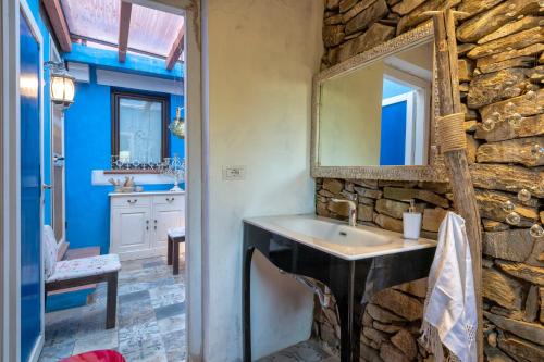 a stone bathroom with a sink and a mirror at Villa Sa Pintadera private pool in Stintino