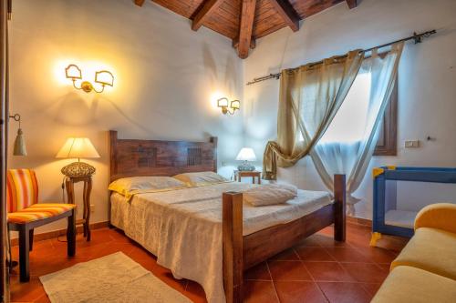 a bedroom with a bed and a chair and a window at Villa Sa Pintadera private pool in Stintino