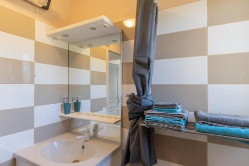 a bathroom with a sink and a mirror and towels at Gîte Chêne ou Murier in Les Vans