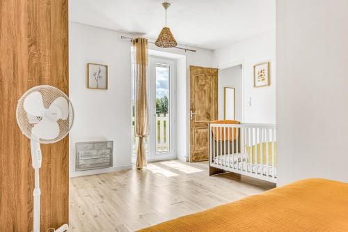 a bedroom with a crib and a room with white walls at Gite Barrail du Moulin in Bégadan
