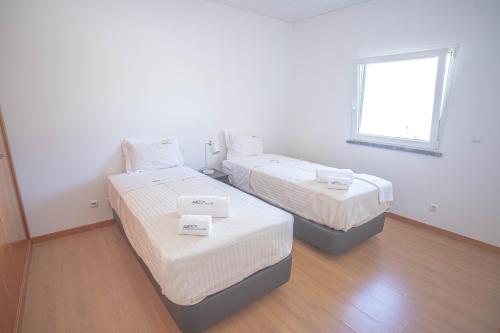 two beds in a white room with a window at Forest Village Exótic in Bolembre de Baixo