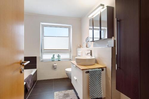 a bathroom with a sink and a toilet and a window at Fewo am Hennesee in Meschede