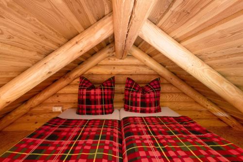 a bed with two pillows in a wooden attic at Chalet am See - Vogtland Chalet in Bad Brambach