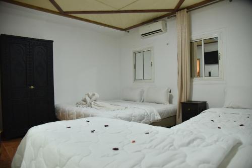 two beds in a room with white sheets at Auberge Resto Agnaoue in Marrakesh