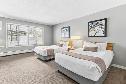 two beds in a room with two windows at North Star Lodge & Resort in Killington